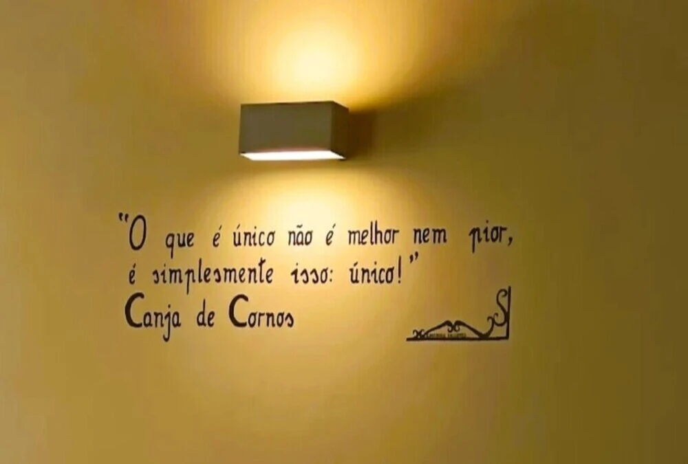 Parede com inscrição "Canja de Cornos" e frase sobre ser único, iluminação suave no restaurante Zé Nabeiro.