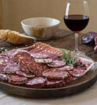 Tábua de chouriço fatiado com taça de vinho tinto Beira Interior.