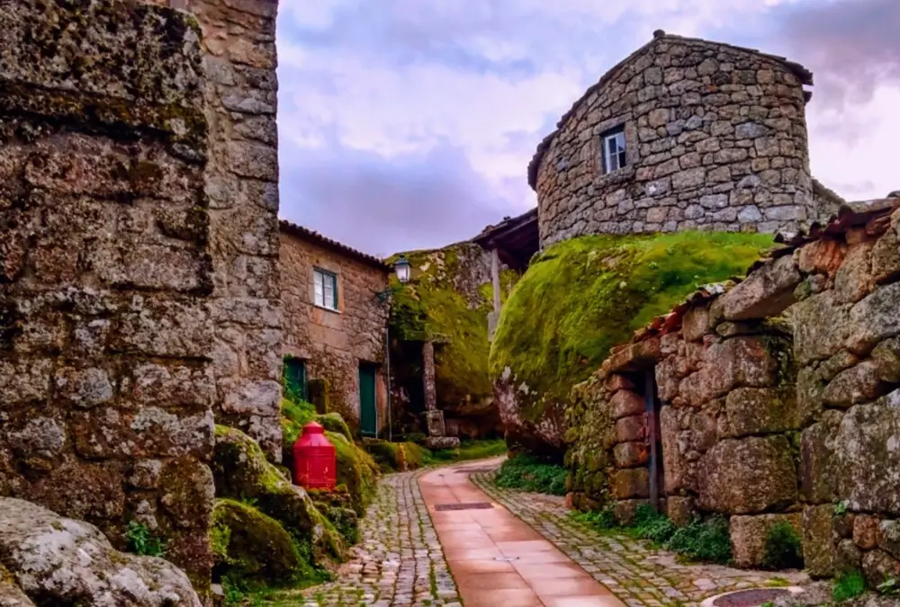 Ruela estreita de Monsanto com casas construídas entre blocos gigantes de granito.