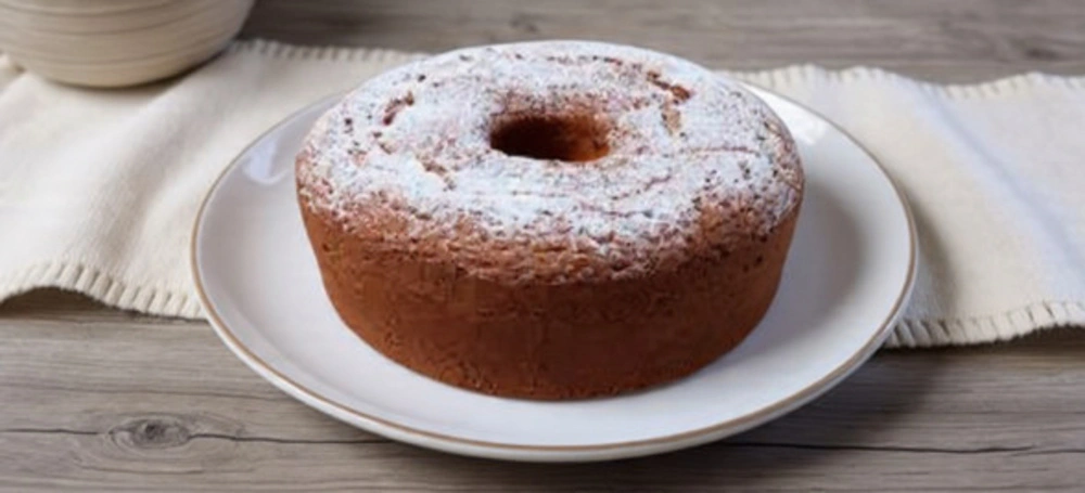 Bolo de azeite fofo com açúcar em pó em mesa rústica, especialidade do Sabugal.