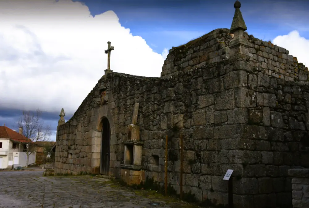 Igreja de pedra antiga com cruz no topo em Alfaiates, concelho do Sabugal, Portugal.