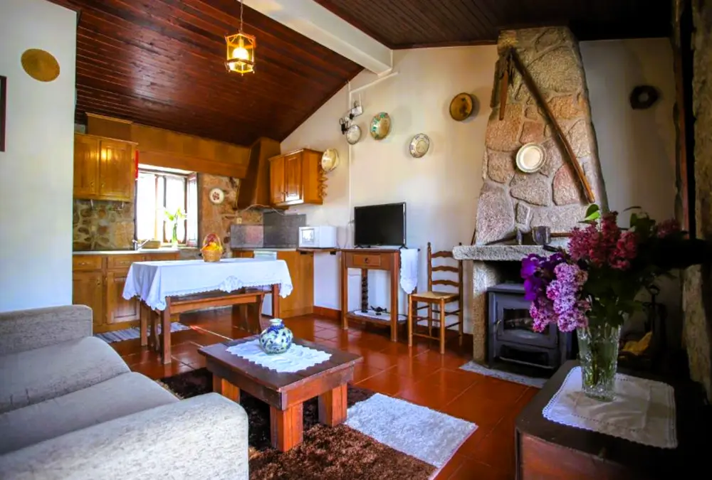 Sala com lareira de pedra e mesa de madeira.