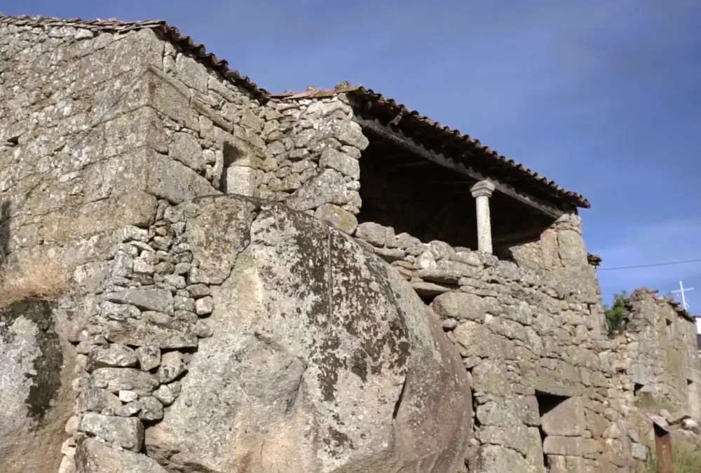 Fachada de uma casa tradicional construída inteiramente em blocos de granito em Vila do Touro, fundindo-se com a rocha natural.
