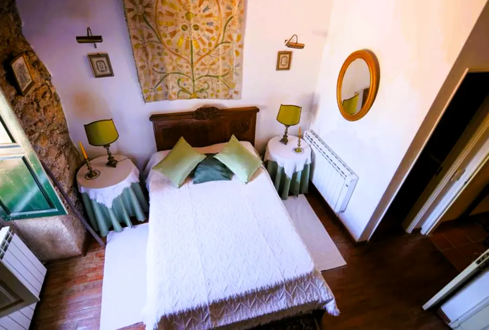 Quarto aconchegante com espelho dourado e tapete de parede.
