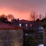 Entardecer com céu rosado sobre o pelourinho e casas medievais em Sortelha.