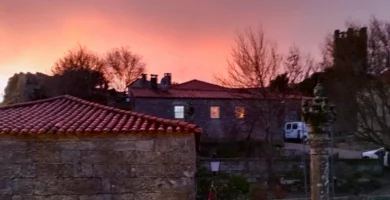 Entardecer com céu rosado sobre o pelourinho e casas medievais em Sortelha.