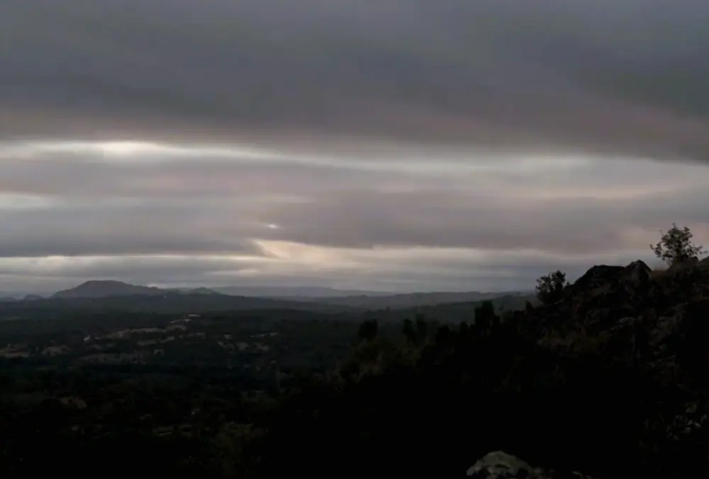 Pôr do sol dourado sobre as colinas e ruínas de Vila do Touro, criando silhuetas dramáticas na paisagem.
