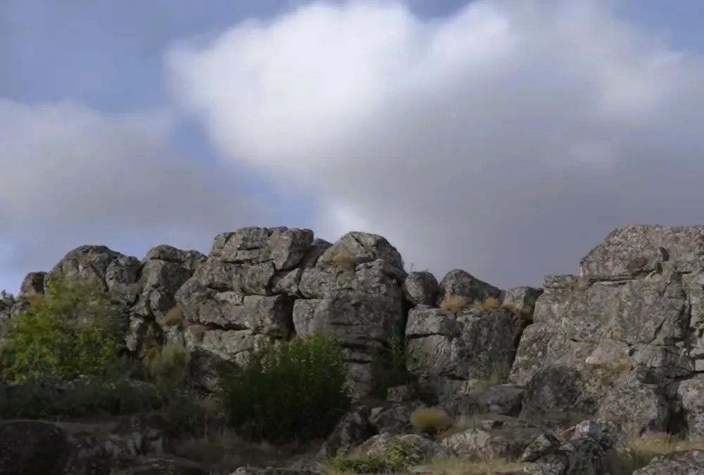 Grande bloco de granito bruto com texturas ásperas e líquenes, típico da região do Sabugal.
