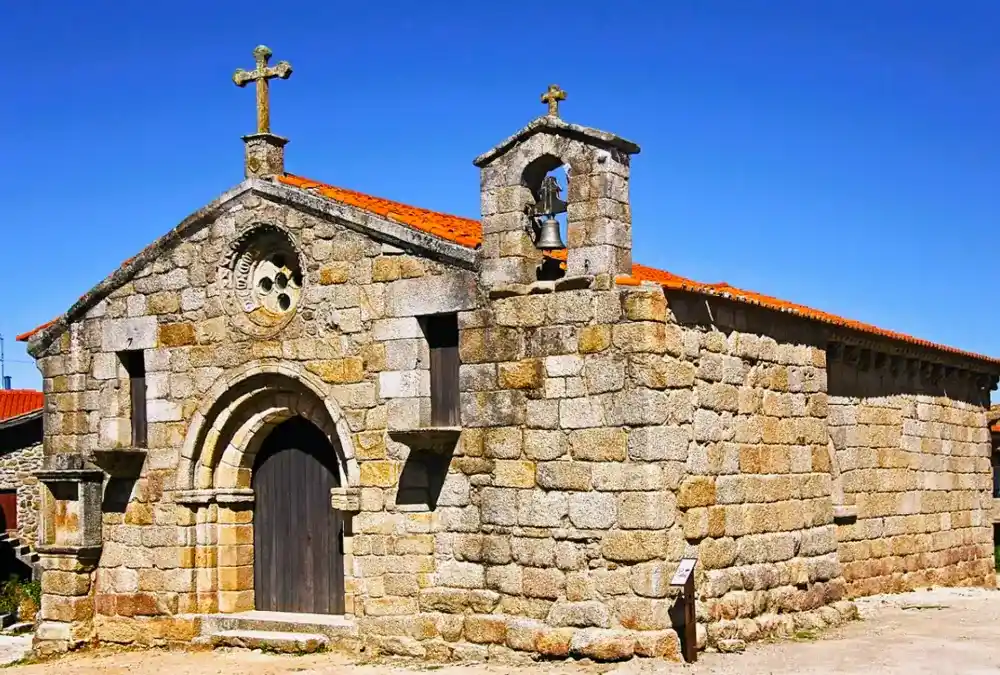 Fachada de granito da Igreja da Misericórdia de Alfaiates, apresentando um portal românico em arco, uma rosácea esculpida e uma pequena torre sineira lateral.