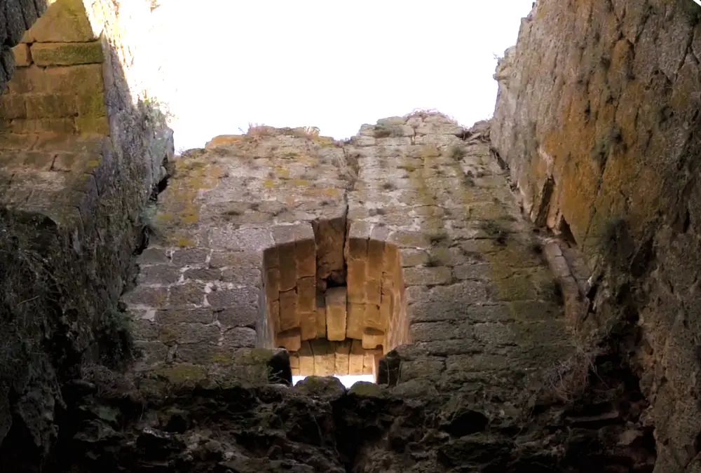 Vista de baixo para cima de uma abertura de janela nas ruínas da torre de menagem do Castelo de Alfaiates, mostrando a espessura das paredes de pedra.