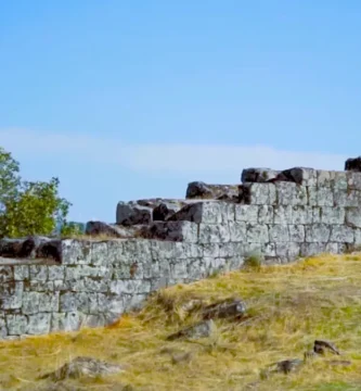Fileiras de muralhas defensivas em degraus feitas de pedra sobre uma colina gramada em Vila do Touro.
