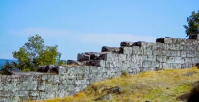 Fileiras de muralhas defensivas em degraus feitas de pedra sobre uma colina gramada em Vila do Touro.