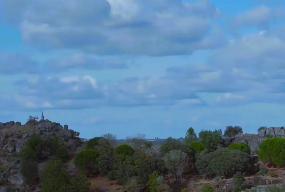  Paisagem natural de Vila do Touro com céu azul, nuvens brancas e vegetação densa de árvores e arbustos.