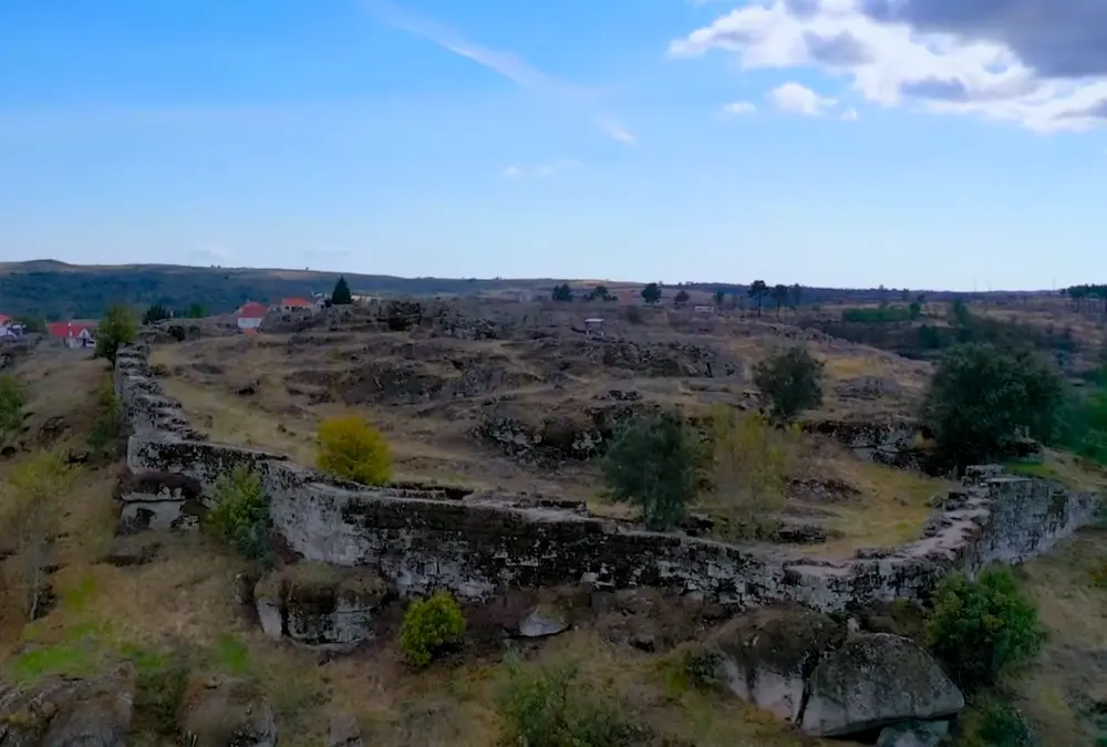 Vista panorâmica dos restos das muralhas do castelo de Vila do Touro serpenteando o cume da montanha.