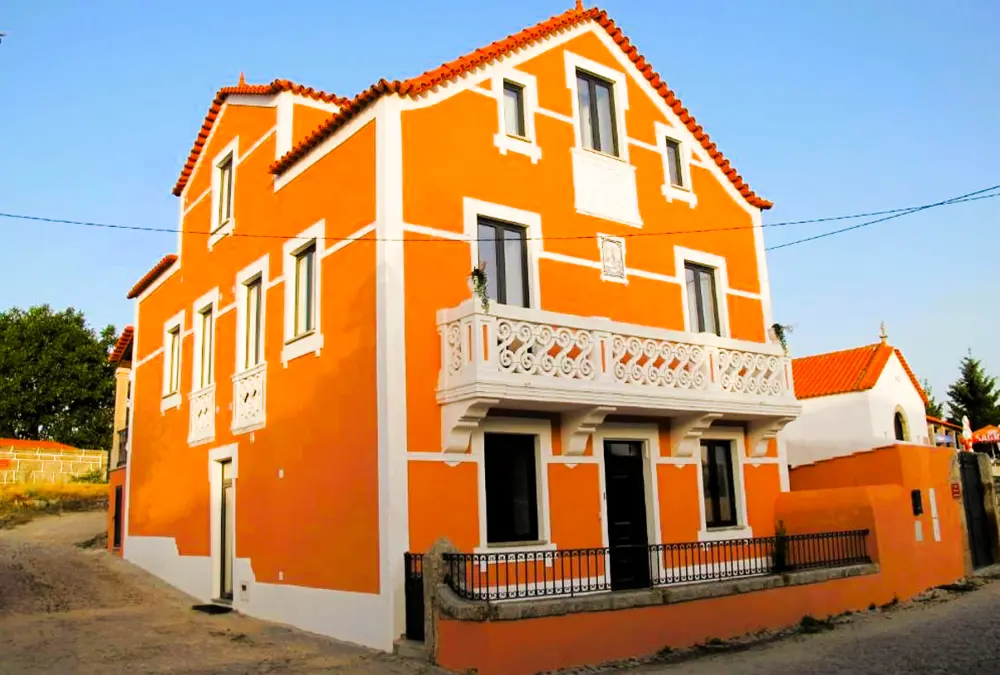 Casa tradicional de cores vibrantes numa rua típica, uma opção charmosa para ficar em Vila do Touro, no Sabugal.