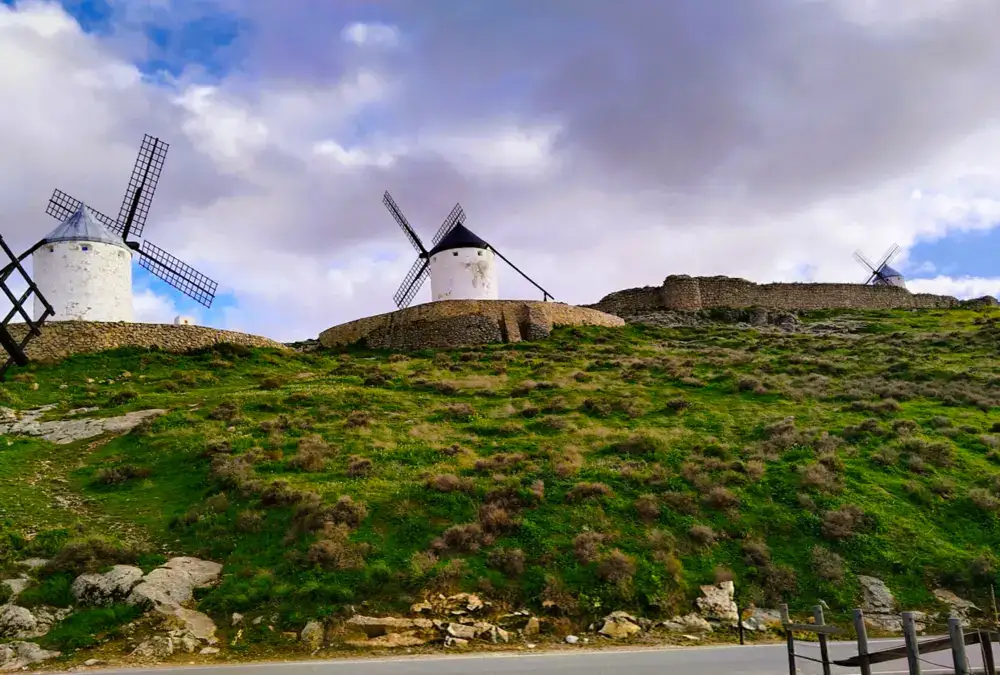 · Vista de uma das estradas secundarias para fotografos com moinhos de vento brancos sobre uma crista rochosa e o castelo de Consuegra ao fundo.