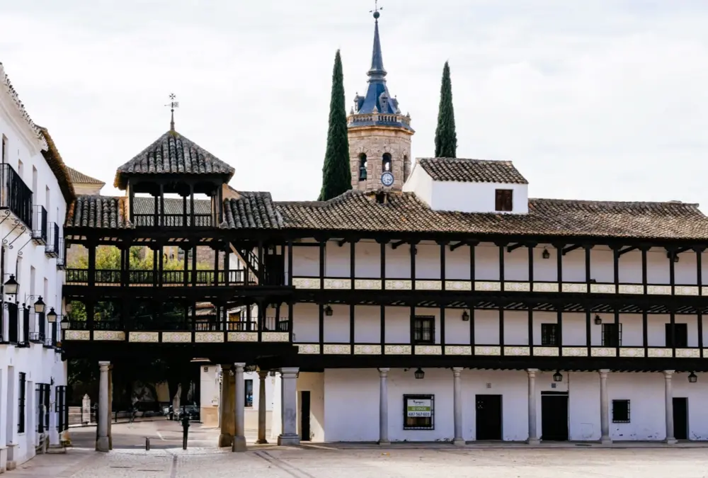 Plaza Mayor de Tembleque com galerias de madeira de três andares e torre da igreja ao fundo.