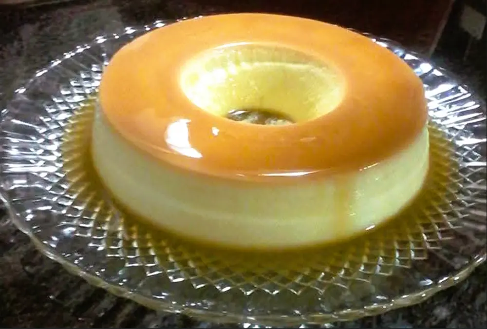 Pudim caseiro com calda de caramelo num prato de vidro.