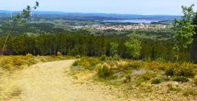Vista panorâmica de um trilho no Sabugal com a Albufeira da Meimoa ao fundo sob um céu nublado.