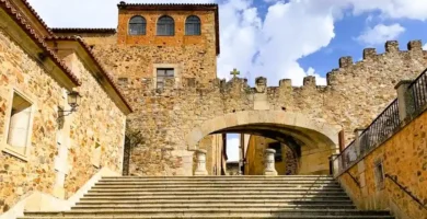 Vista detalhada do Arco de la Estrella, a principal porta de entrada para a cidade velha medieval de Cáceres, mostrando o brasão de armas e a torre adjacente.