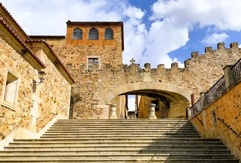 Vista detalhada do Arco de la Estrella, a principal porta de entrada para a cidade velha medieval de Cáceres, mostrando o brasão de armas e a torre adjacente.