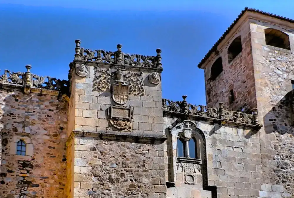 Fachada de um palácio renascentista no centro histórico de Cáceres, construído em pedra de cantaria com brasões familiares esculpidos na fachada.