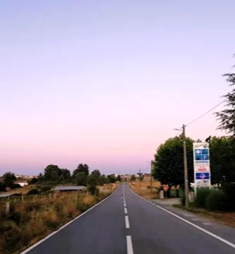 Estrada secundária reta e vazia durante o pôr do sol, representando o conceito de Slow Travel e tranquilidade.