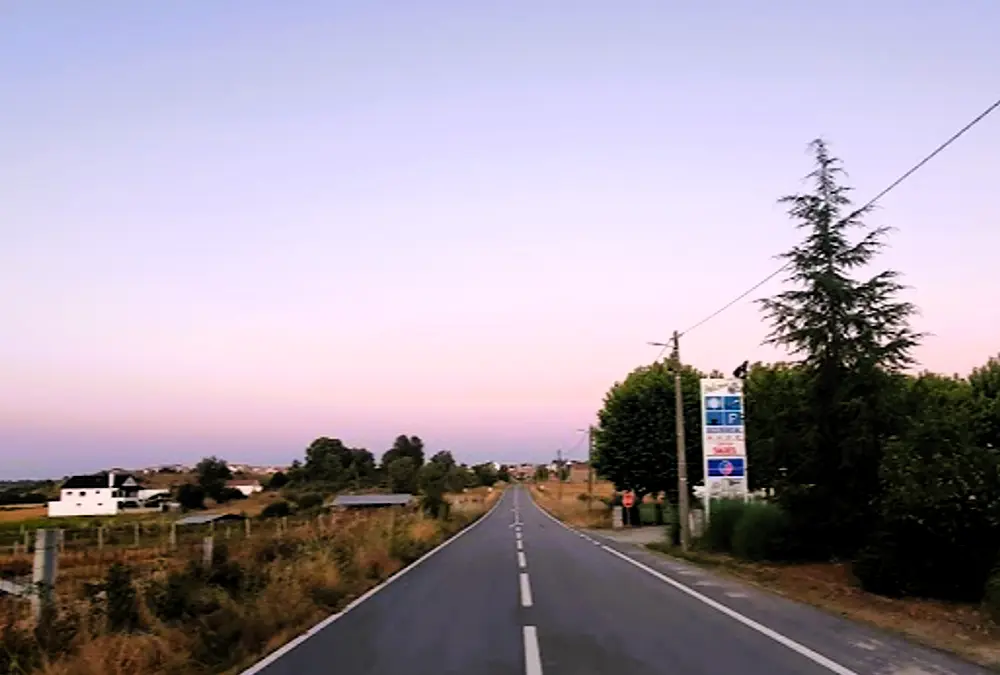 Estrada secundária reta e vazia durante o pôr do sol, representando o conceito de Slow Travel e tranquilidade.