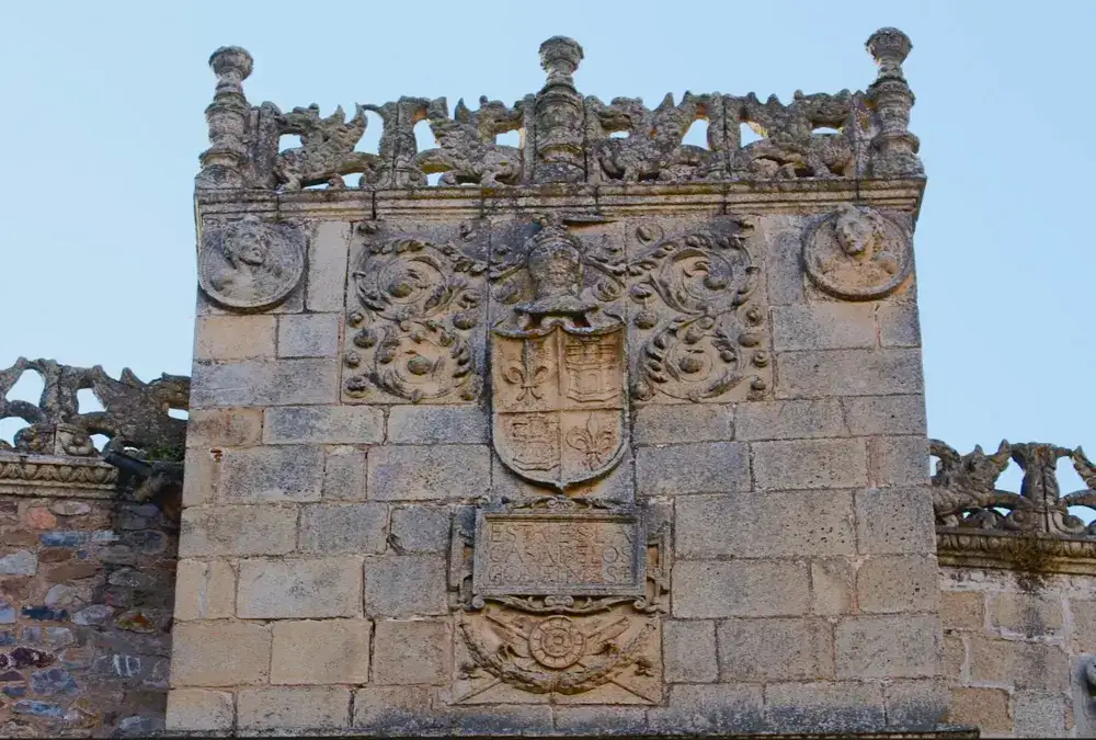 Detalhe de uma varanda renascentista ornamentada e um brasão nobre esculpido em pedra na fachada do Palacio de Golfines de Abajo em Cáceres.