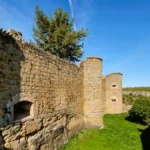 Vista lateral das robustas muralhas e torreões circulares do Castelo de Pedraza, construídos em alvenaria de pedra.