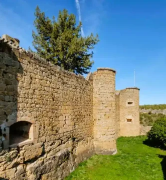 Vista lateral das robustas muralhas e torreões circulares do Castelo de Pedraza, construídos em alvenaria de pedra.