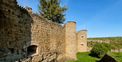 Vista lateral das robustas muralhas e torreões circulares do Castelo de Pedraza, construídos em alvenaria de pedra.