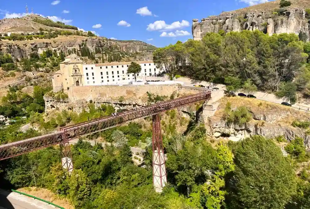Vista ampla da Puente de San Pablo em Cuenca, a ponte pedonal vermelha de ferro que atravessa o desfiladeiro do rio Huécar em direção ao antigo convento e Parador.