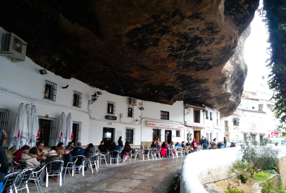 Esplanadas e esplanadas de cafés embutidas sob a rocha colossal na rua Cuevas del Sol em Setenil de las Bodegas.