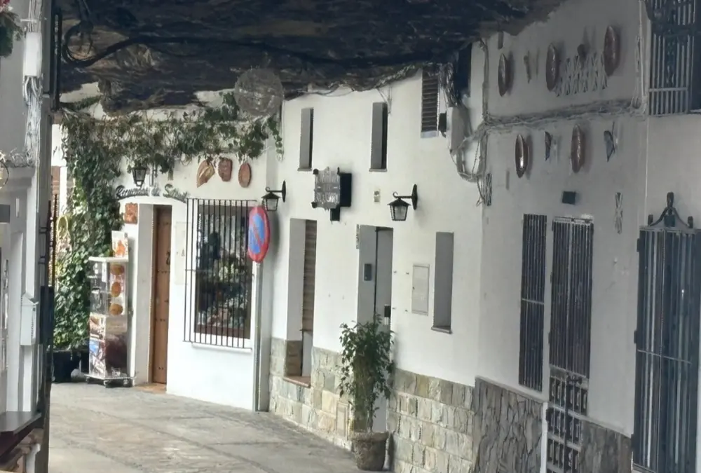 Rua estreita em Setenil de las Bodegas com uma enorme rocha natural a servir de teto sobre as fachadas das casas brancas.